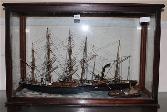 A cased display of sailing ships and a tug
